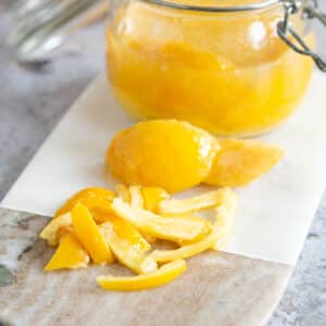 A jar of preserved lemons next to a preserved lemon chopped and ready to add to a dish.