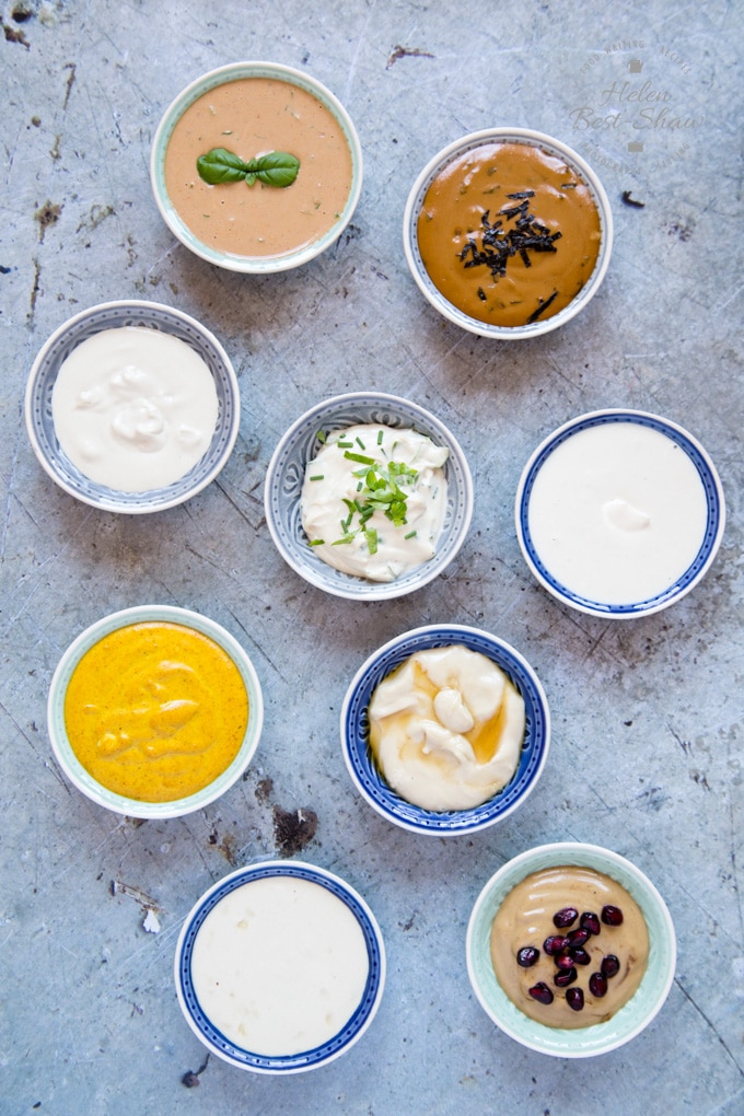 8 small bowls of tahini dressing on a discressed metal background viewed from above. 