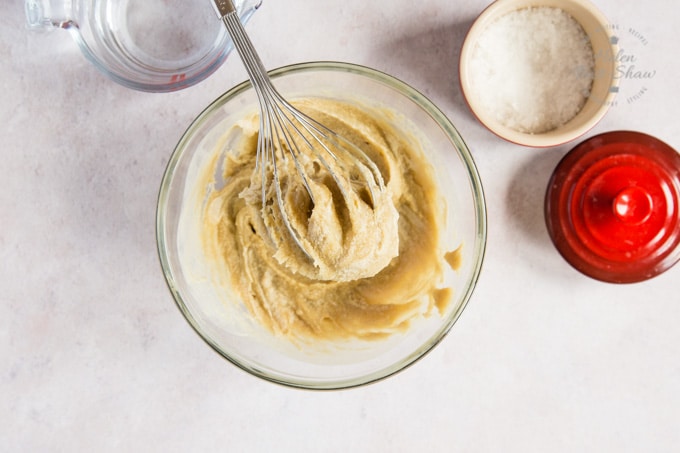 A bowl of thick tahini dressing with a whisk 