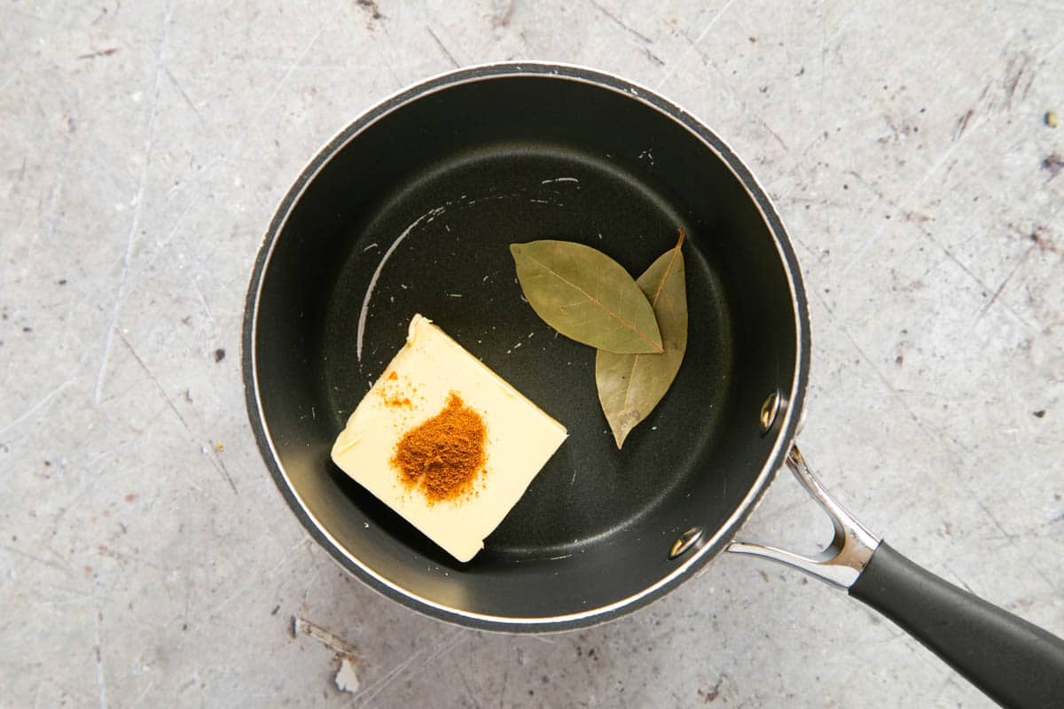 The butter, spice and bay leaves in a pan.