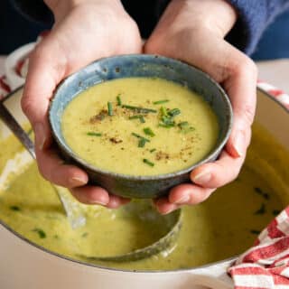 Holding a bowl of warming celery and lentil soup.