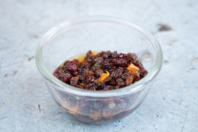 A glass bowl of dried fruit soaking in brandy