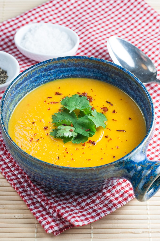 A blue bowl of golden yellow carrot and sweet potato soup