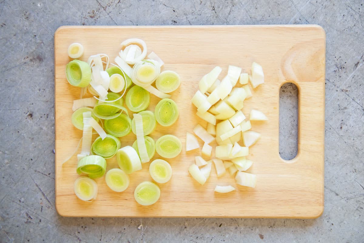 The leek and onion chopped on a wooden board.