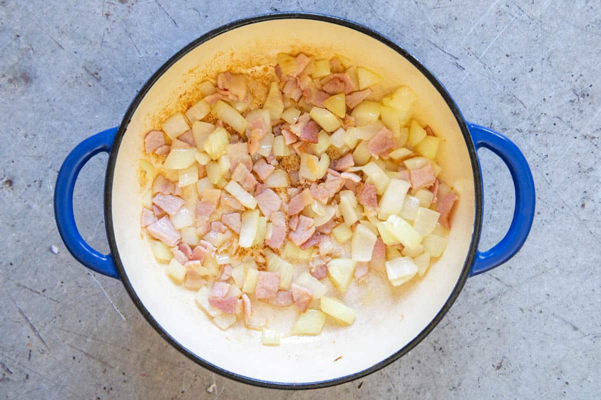 Frying the onion and bacon in the casserole dish.