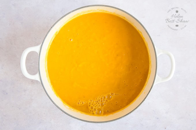 A pot of freshly made golden orange spiced pumpkin soup