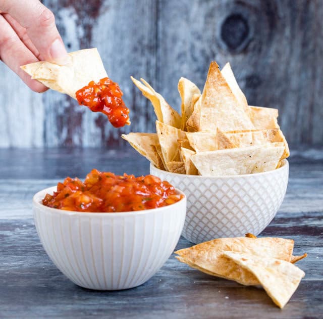 Crispy baked homemade tortilla chips are perfect for your favourite dip like this tomato salsa.