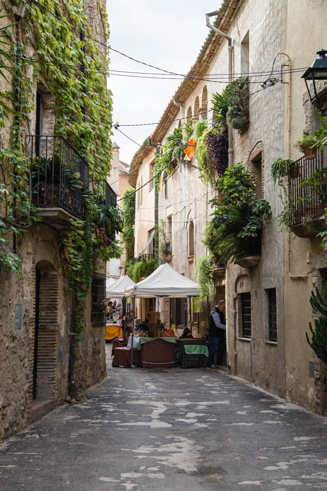 Shaded street in Ventalló, Catalonia with market stalls 
