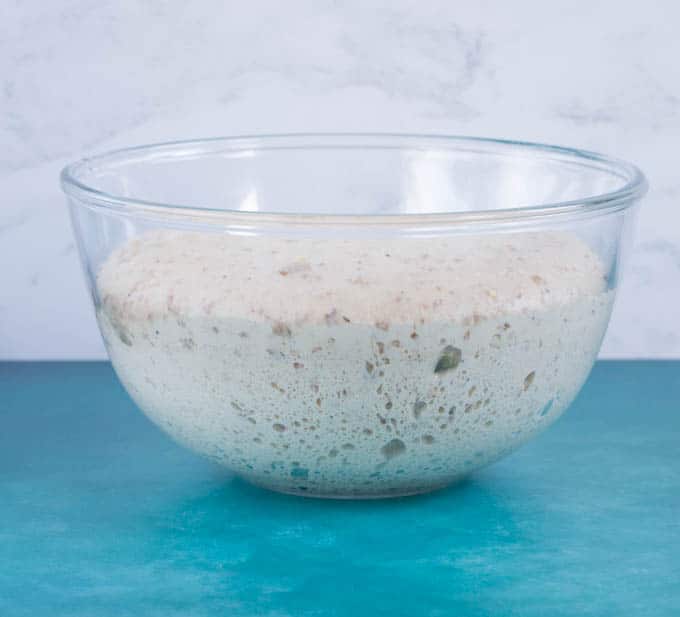 A glass bowl of aerated and risen kefir dough,