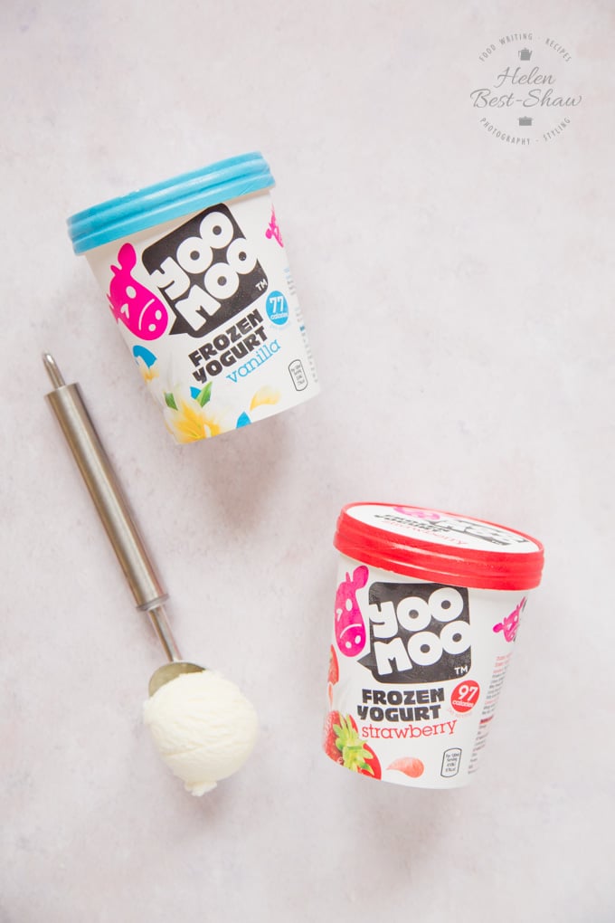 Two tubs of yoomoo frozen yogurt, and an ice cream scoop filled with fro-yo