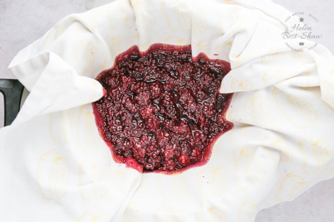 Stewed blackberries for one pot blackberry jelly. The blackberries have been placed in a cloth in a colander so that the juice can drain out.