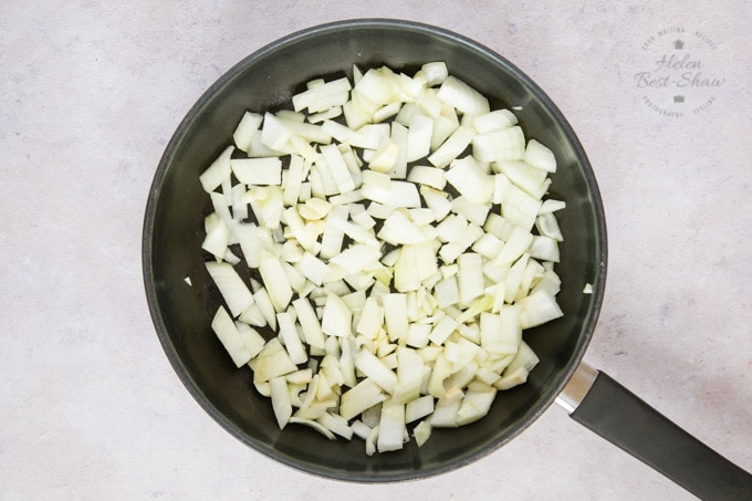 A top down picture of a frying pan full of onion ready to be cooked.