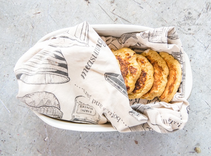 A top down view of four mango pancakes, wrapped in a tea towel in a dish. The best way of keeping pancakes warm in the oven.