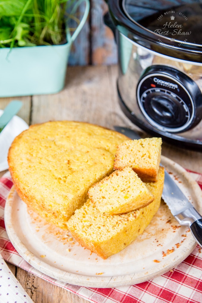 Cornbread in front of a slow cooker/crockpot. Half the cornbread has been cut into cubes.