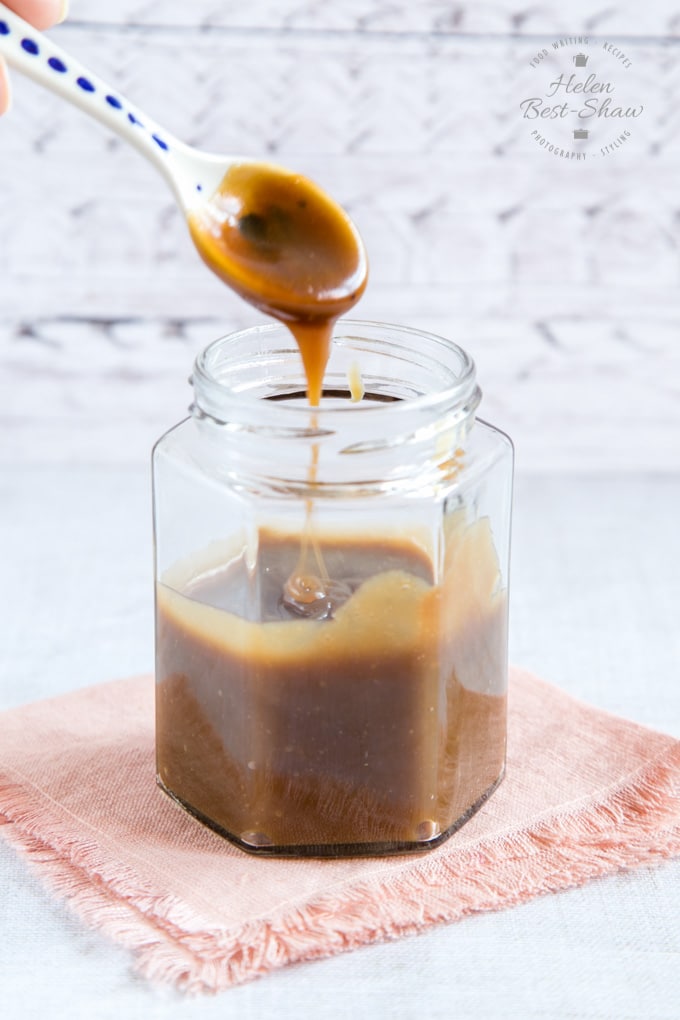 A jar of sauce made from our fudge sauce recipe; sauce drips from a spoon.