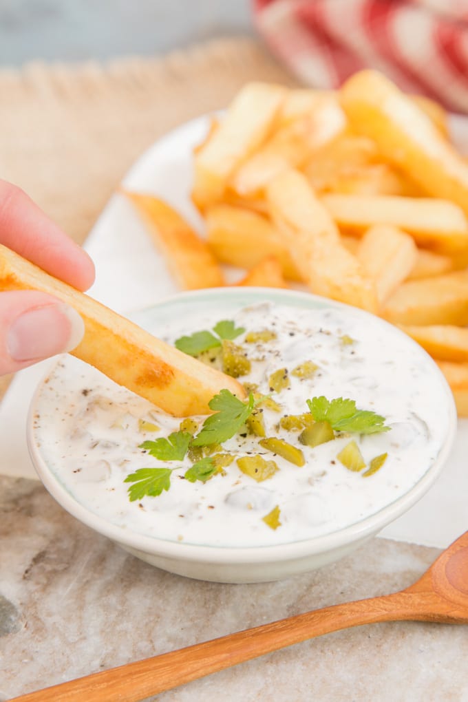 Dipping a chip into rich and thick tartare sauce.