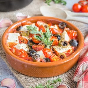 A close up of a dish of baked feta and tomatoes.