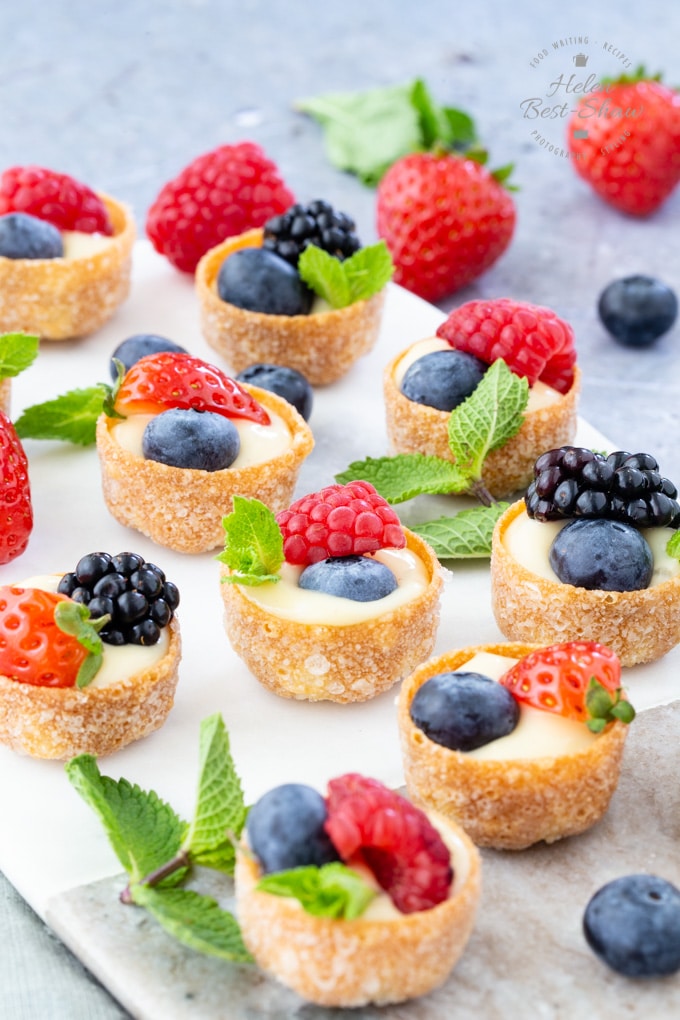 A close up on mini fruit tarts filled with creme patissiere and soft fruit