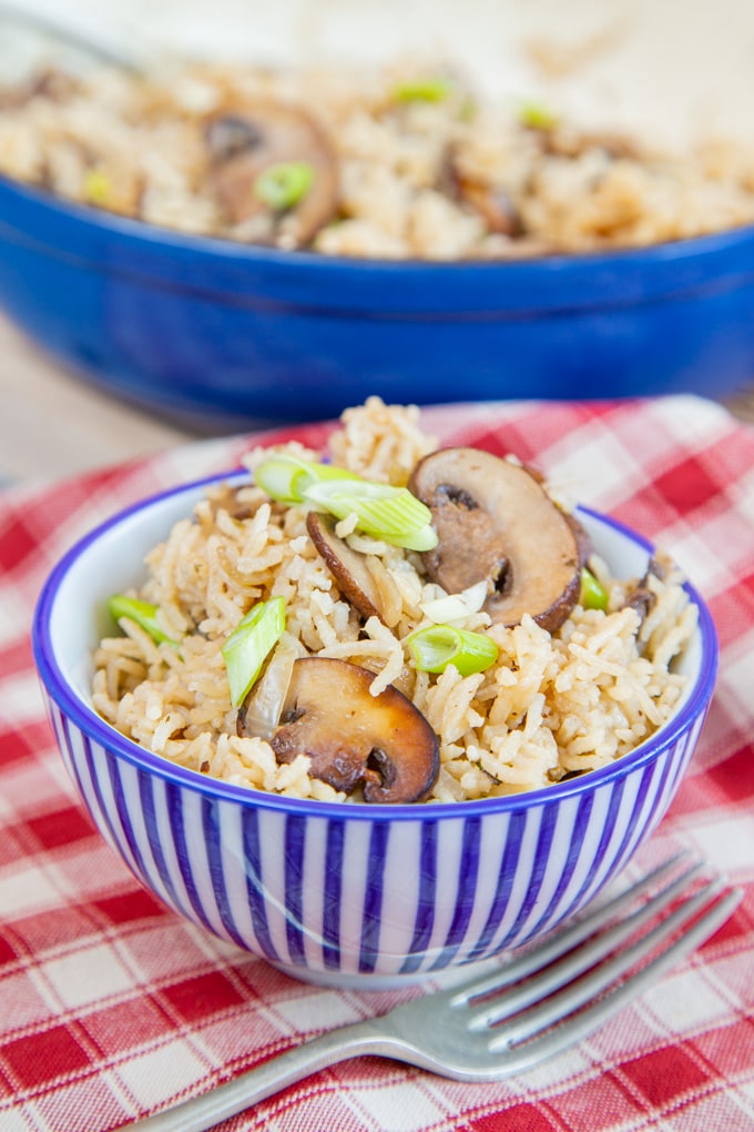 A bowl of fluffy mushroom rice on a red and white gingham cloth.