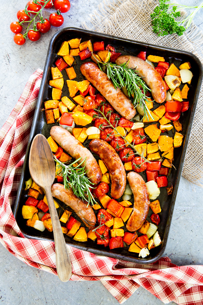 Sausage traybake with butternut squash, tomatoes, peppers, garlic and onion, ready to eat.