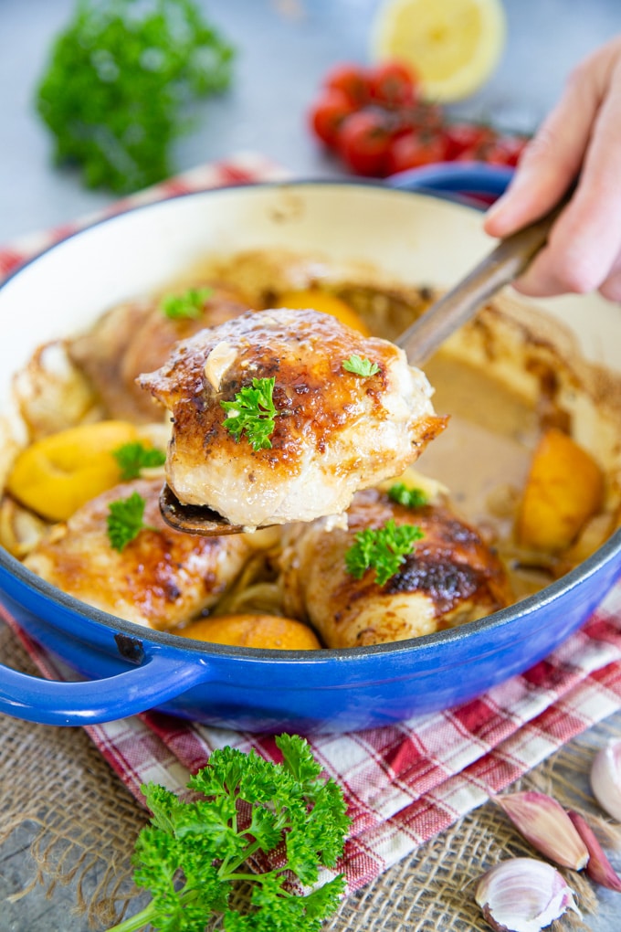 Serving a honey mustard chicken thigh from a blue and white casserole dish.