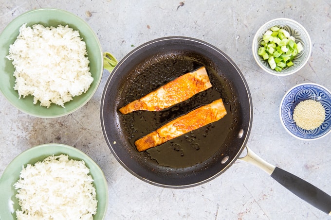 A picture from above of salmon fillets placed back in the frying pan to coat with teriyaki sauce.