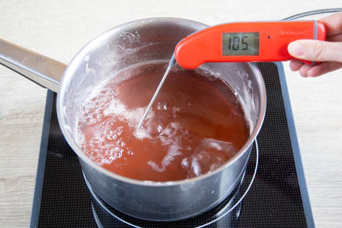 A saucepan of crab apple jelly; checking the temperature to see if its reached setting point.