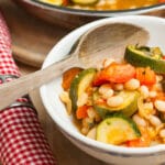 Close up of a white bowl of ratatouille with haricot beans.