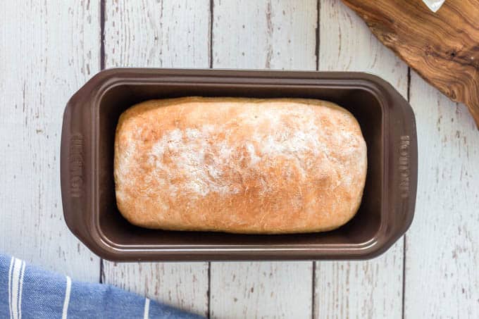 Baked yogurt bread with a golden crust, in a black loaf tin.