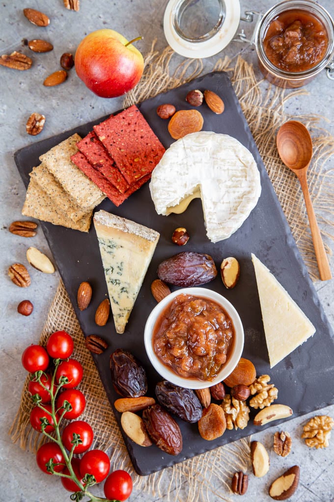 Apple and plum chutney, surrounded by nuts, cheese, biscuits and fruit