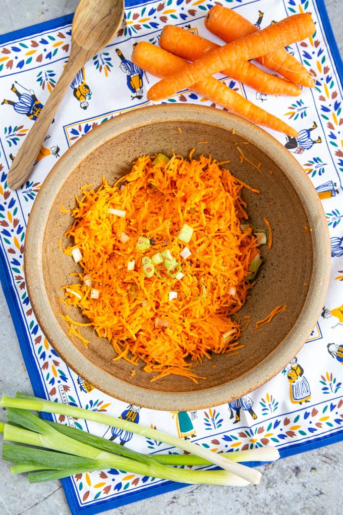 A top down view of easy carrot salad, garnished with slices of scallions.