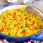A close up of yellow Nandos Portuguese spicy rice with green peas and pieces of red pepper