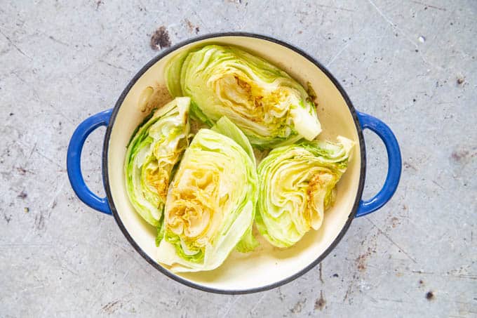 Browned fried quarters of iceberg lettuce in a shallow casserole dish.