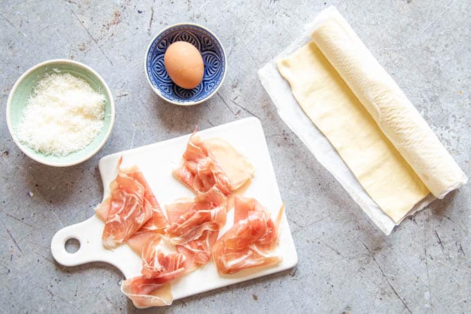 Ingredients for prosciutto cheese twists - pastry, grated cheese, ham and an egg.
