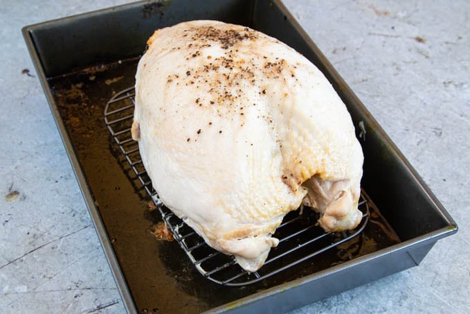 Half cooked turkey crown on a rack, in a roasting tray.