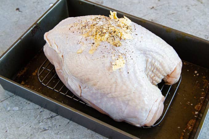 A raw turkey crown on a roasting tray, with butter,