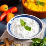 A close up of a blue dish of cucumber raita