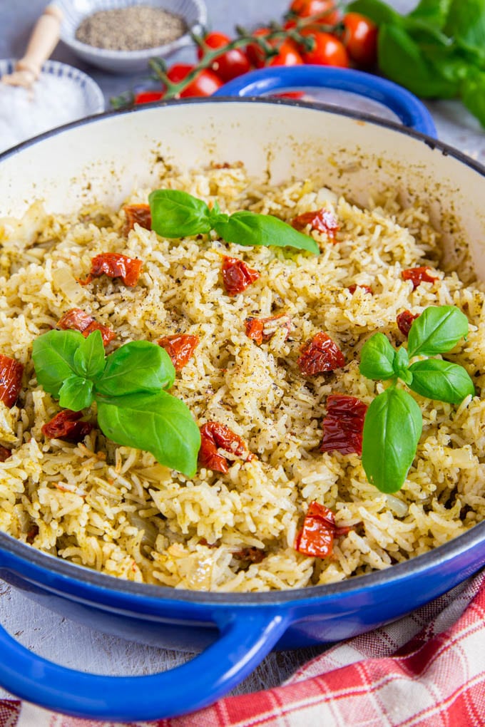 A blue shallow casserole dish full of Italian rice fills the frame. It's garnished with basil.