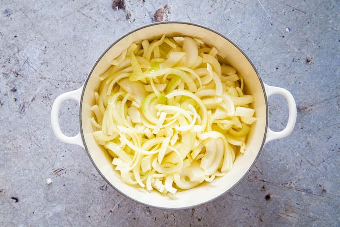 A casserole dish full of sliced onions, ready for cooking.