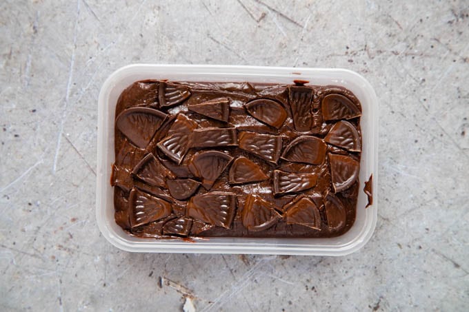 A takeaway tray full of chocolate orange fudge decorated with small pieces of chocolate orange