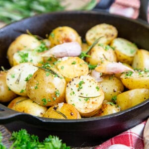 A close up of a dish of baby roast potatoes, garnished with chopped parsley.