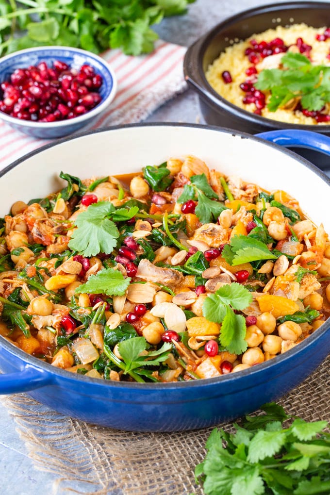 Turkey tagine with side dishes; a bowl of couscous, and one of pomegranate seeds.