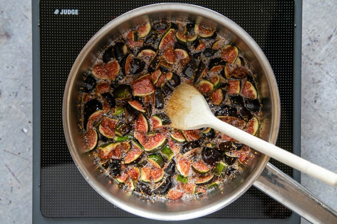 Figs in a saucepan, ready to be cooked. A wooden spoon sits in the saucepan.
