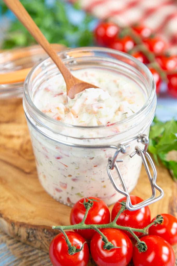 Close up of a glass jar filled with sandwich spread standing on a wooden board