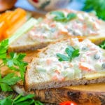 Close up of a wooden board with two slices of bread spread with sandwich spread