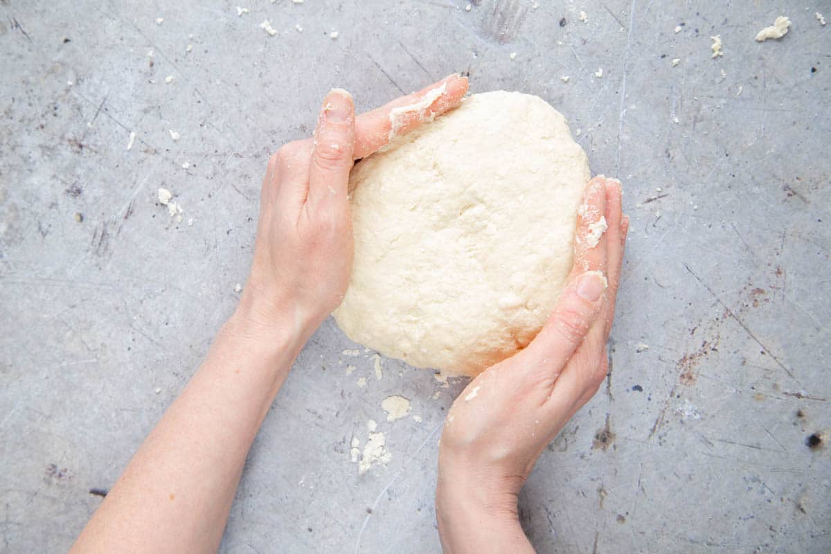 Forming self raising flour dough into a round, flat pancake about 2.5cm or 1 inch thick.