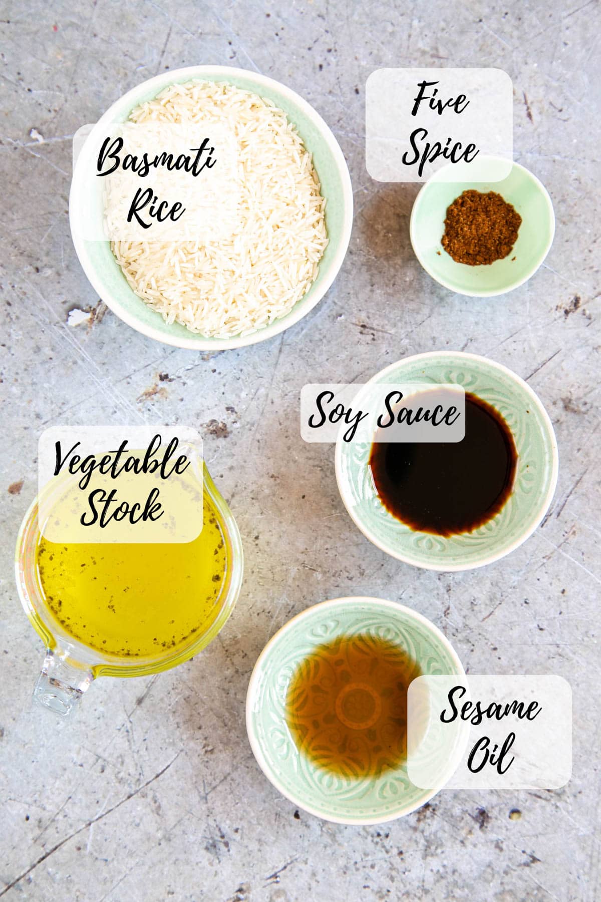 The ingredients for easy Chinese rice: rice, five spice, soy sauce, vegetable stock and sesame oil. An annotated top down picture of all these ingredients.