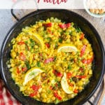 Top down picture of golden yellow easy vegetable paella, with olives, chickpeas and slices of red peppers, ready to serve.