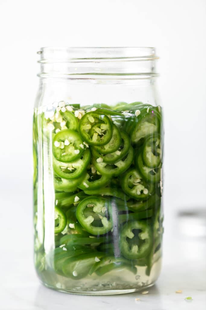 A jar of sliced green pickled chillies
