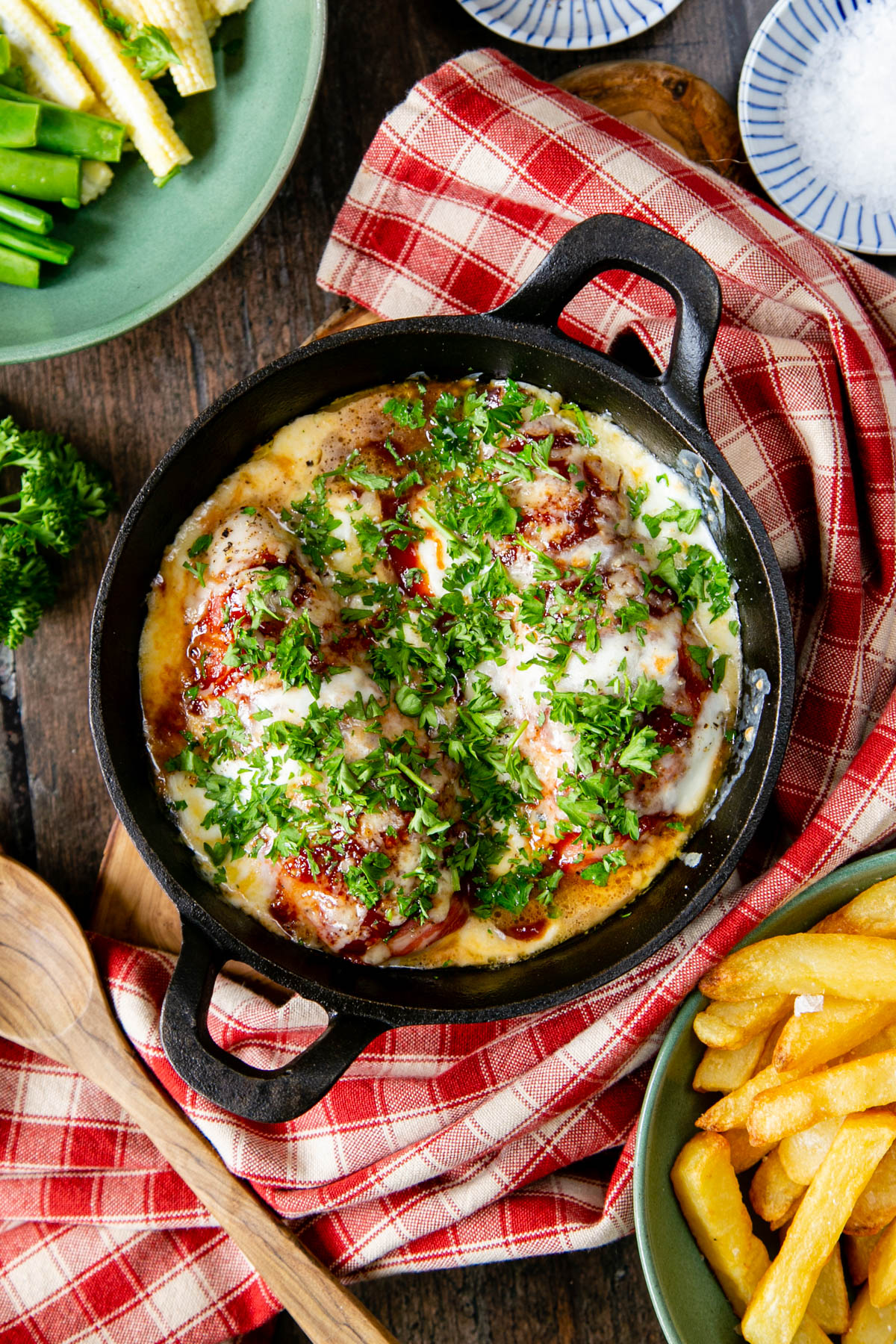 A cast iron dish of hunters' chicken. 2 breasts nestled nest to each other, with plenty of sauce, all garnished with vibrant green chopped parsley.
